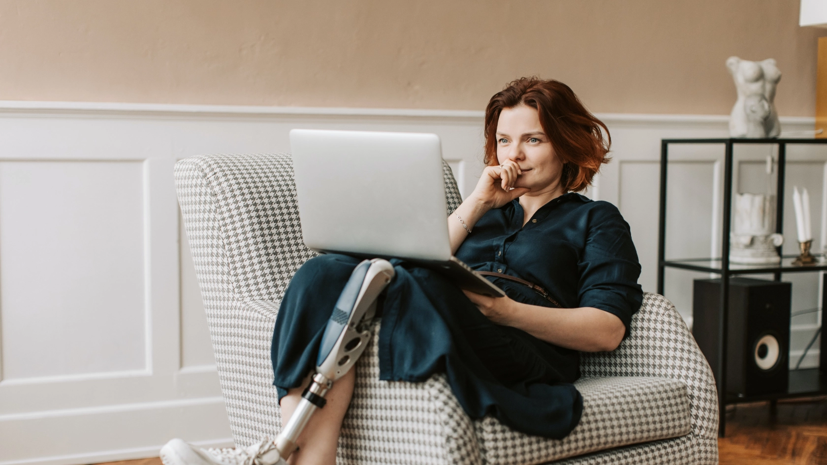 Frau mit Beinprothese lümmelt sich auf ein Sofa und liest in einem Laptop