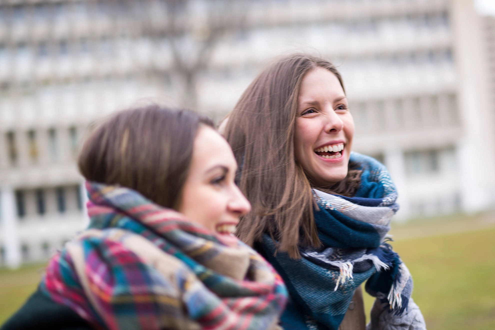 Zwei junge lachende Frauen auf dem Campus.